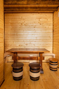 Yeni, modern bir ahşap kulübenin odasının etrafında şarap fıçıları şeklinde küçük tahta tabureleri olan ahşap bir masa. Fıçılar sicim ve işlenmiş demir çemberlerle süslenir..