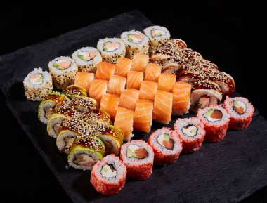 Farklı türde suşi setiyle büyük kare taştan bir tahta. Geleneksel Japon mutfağı. Sashimi ve nigiri sushi..