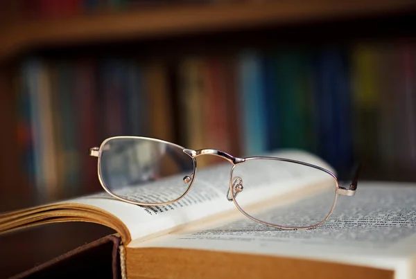 Bril op een boek in de bibliotheek — Stockfoto