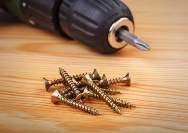 Taladro inalámbrico y tornillos grandes sobre un fondo de madera — Foto de Stock