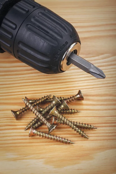 Taladro inalámbrico y tornillos grandes sobre un fondo de madera — Foto de Stock