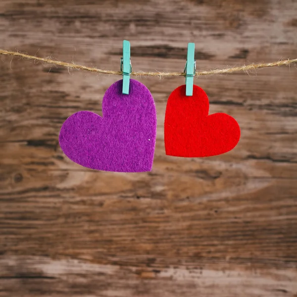 Dos corazones colgando de un cordón sobre un fondo de madera —  Fotos de Stock