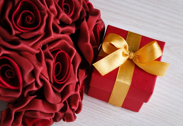 Rode bloemen en cadeau doos met geel lint — Stockfoto
