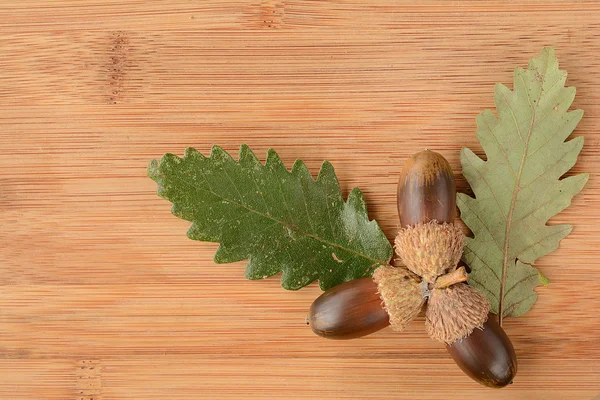 Eiken acorn en bladeren op houten achtergrond — Stockfoto