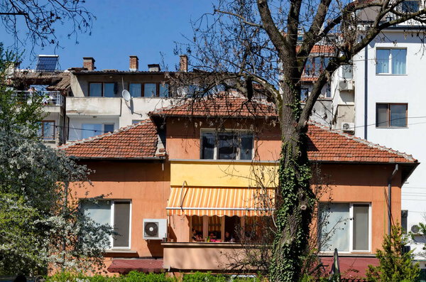 София, Болгария - 25 апреля 2021 года: Цветущие весенние деревья на фоне жилого района со старыми домами, София, Болгария. Висит на месте.