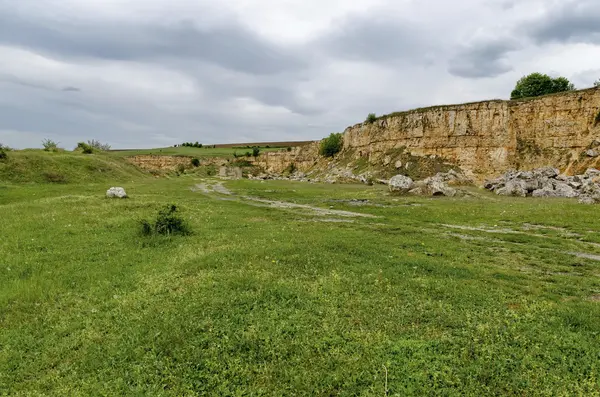 General view toward crag of sedimentary rock in the field — Stock Photo, Image