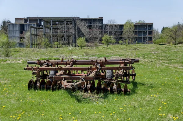 Verlassene unvollendete Gebäude und landwirtschaftliche Maschinen — Stockfoto