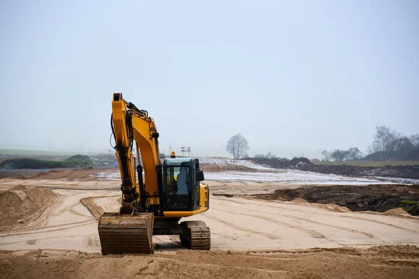 Excavator digs sand at road construction.