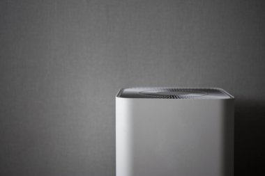 Gri duvar arka planında beyaz hava temizleyicisi.