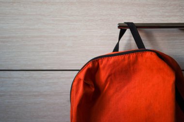 Rafta asılı parlak turuncu okul çantası.