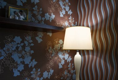 Masa lambası yatak odasındaki masada loş bir şekilde parlıyor..