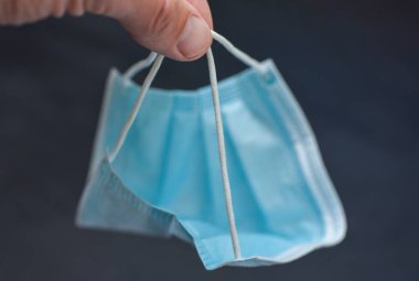 El, siyah arka planda tıbbi gazlı bez maskesi atar..