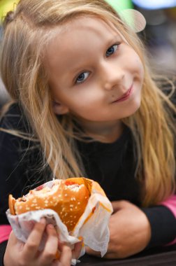 Fast food kafede hamburger yiyen küçük kız..