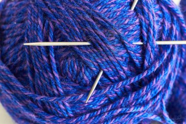 İplik yumağı ve beyaz arka planda örgü iğneleri. Kapat..