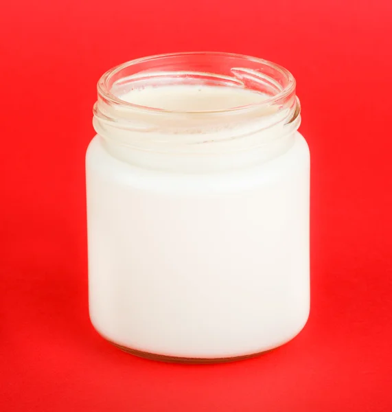 Jar with yogurt isolated on red background — Stock Photo, Image