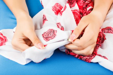 Seamstress is sewing cloth herself.