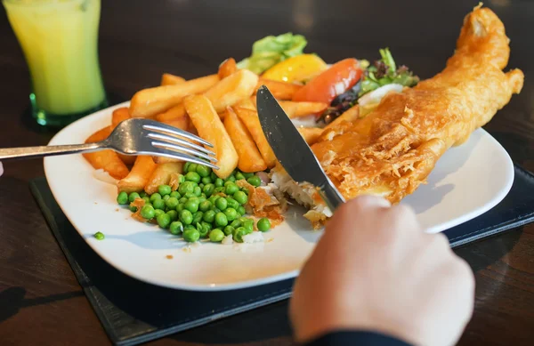 Uma mulher comendo peixe e batatas fritas — Fotografia de Stock