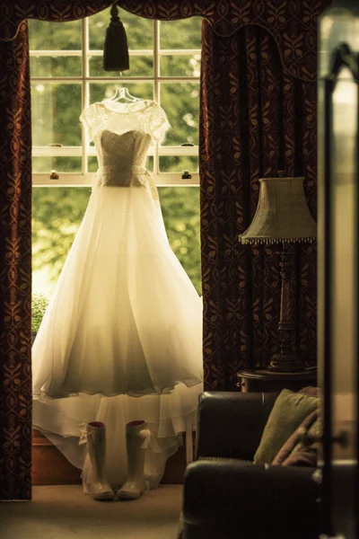 Снимок элегантного свадебного платья, висящего над окном — стоковое фото