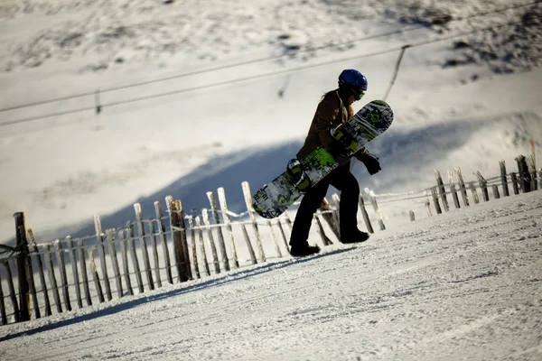 Bir tepeye yürüyüş bir snowboarder — Stok fotoğraf