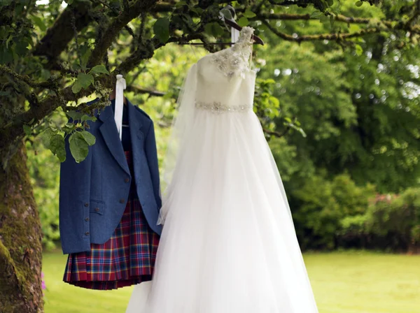 Килт и свадебное платье висят на дереве — стоковое фото