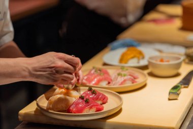 Suşi şefi canlı bir suşi tabağı hazırlıyor. Taze malzemelerle birlikte. Mutfak sanatını gözler önüne seriyor ve detaylara dikkat ediyor..