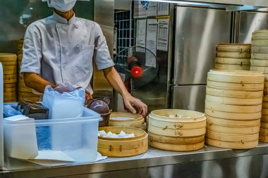 Kuala Lumpur, Malezya - 2 Ağustos 2024: Asyalı şef, yoğun bir mutfak ortamında bambu budan buharlı tencere kullanarak Çin yemeği hazırlıyor.