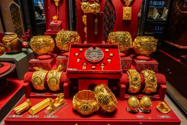 Kuala Lumpur, Malezya - 2 Ağustos 2024: Altın mücevherler güzel bir şekilde kırmızı ekranda düzenlenmiştir karmaşık tasarımlar ve lüks dokular.