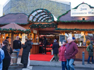 Berlin, Almanya - 01 Ocak 2024: Noel pazarında neşeli dekorasyonlar ve atmosferin tadını çıkaran alışveriş düşkünleri yer alıyor.