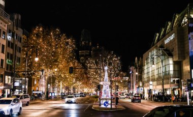 Berlin, Almanya - 01 Ocak 2024: Gece şehir caddesi şenlikli ışıklarla bezenmiş canlı bir tatil atmosferi yaratıyor.