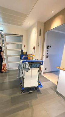 Belin, Almanya - 30 Mayıs 2025: Hastane koridorunda bir sağlık arabası ve sağlık görevlisi yürüyor. Hastane