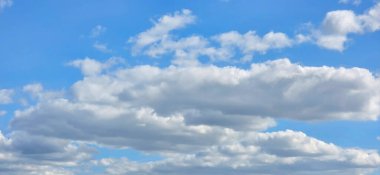 Yumuşak beyaz bulutlar parlak mavi bir gökyüzünde süzülüyor. Hafif güneş ışığıyla aydınlatılıyor. Huzurlu ve huzurlu bir atmosfer yaratıyor..