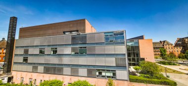 Berlin, Almanya - 13 Mayıs 2025: Modern mimari yapı arka planda yeşil peyzaj ve açık mavi gökyüzüne sahiptir.