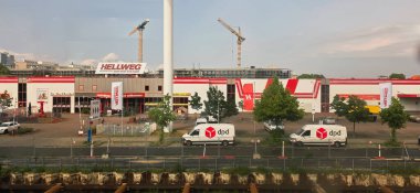 Berlin, Almanya - 02 Haziran 2025: Hellweg nalbur mağazası arka planda dağıtım kamyonetleri ve inşaat alanlarını barındırıyor.