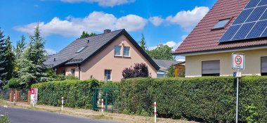 Berlin, Almanya - 4 Temmuz 2025: Bereketli yeşillik ve açık mavi gökyüzü ile çevrili güneş panellerinin yer aldığı iki mesken.