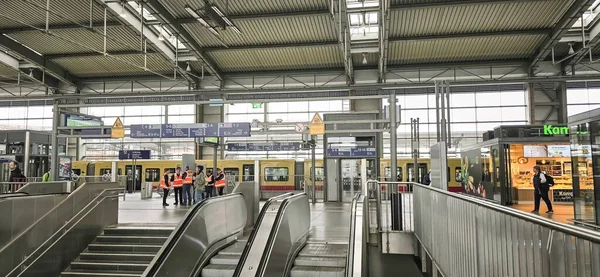 Belin, Almanya - 19 Mayıs 2025: Modern tren istasyonu iç mekanında yürüyen merdiven ve yolcular yer alıyor.