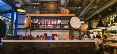 Berlin, Almanya - 08 Mayıs 2025: Modern restoran canlı dekorlu ve canlı yemek atmosferli ahşap bir bara sahiptir.