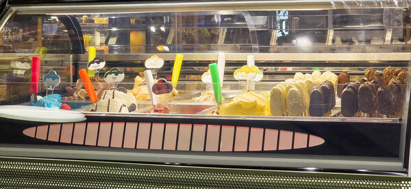 Доломан, Турция - 25 апреля 2025 года: в современном магазине на разноцветной витрине мороженого представлены разнообразные вкусы и ароматы.