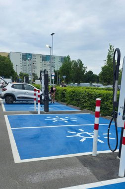 Berlin, Almanya - 28 Haziran 2025: Elektrikli taşıt şarj istasyonu yeşil renkli kentsel alanda park etmiş arabaları içeriyor.