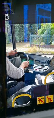 Berlin, Almanya - 07 Ağustos 2025: Otobüs şoförü şehir ortamında gösterge paneli kontrolüyle aracı kullanıyor.