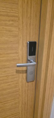 . Modern kapı kolunda ahşap bir kapıda elektronik bir kilit, modern mimaride parlak bir tasarım ve işlevsellik sergileniyor.