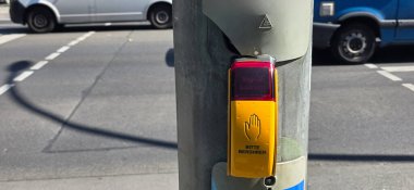 Berlin, Almanya - 3 Temmuz 2025: Yaya trafiği sinyal düğmesi direğin üzerine monte edilmiş ve geçen araçlar