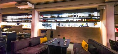 Berlin, Almanya - 07 Ağustos 2025: Modern restoranda şık koltuklar ve canlı bir ortam ile açık mutfak tasarımı yer almaktadır.