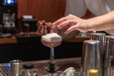 Barmen dikkatlice çırpılmış krema ve dekoratif çiçekle kokteyl hazırlıyor. Detaylara ve miksoloji yeteneklerine dikkat çekiyor..