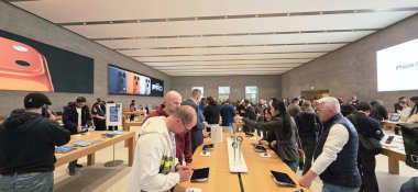 Berlin, Almanya - 22 Eylül 2025: En son iPhone modelleri ve teknoloji görüntülerini inceleyen müşterilerle dolu yoğun Apple Mağazası.