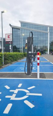 Berlin, Germany - June 28, 2025: Electric vehicle charging station is located outside a modern building with greenery.