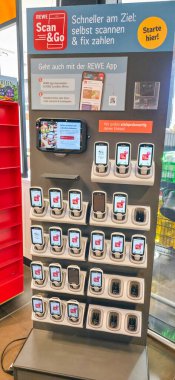 Berlin, Germany - July 04, 2025: REWE Scan and Go self-checkout kiosk displays multiple devices for quick shopping experience.