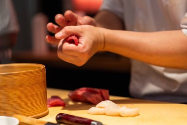 Sushi chef skillfully prepares fresh seafood, showcasing technique and artistry in a vibrant kitchen environment filled with culinary tools.