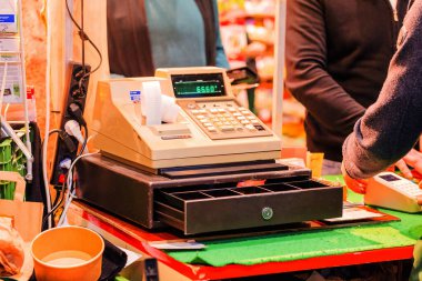Berlin,Germany. 21.01.2025 Cash register displayed on a market stall, featuring an open drawer and various colorful items in the background, creating a lively atmosphere.