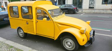 Berlin, Germany - July 18, 2025: . Vintage yellow Citroen 2CV is parked on city street with urban buildings in background