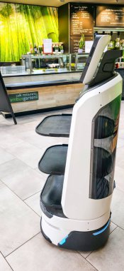 Berlin, Germany - August 06, 2025: . Service robot with trays stands in a modern cafe interior with greenery